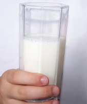 una mano che regge un bicchiere di latte
