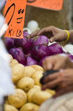 un mercato con delle mani in primo piano che prendono la verdura
