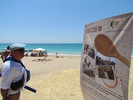 partecipanti sulla spiaggia e cartello della compagnia
