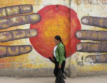 murales con due mani che si cercano davanti a un sole rosso