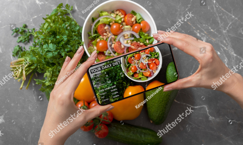 mani di donna che inquadrano con la fotocamera del telefono dei piatti con verdure per utilizzare l'intelligenza artificiale