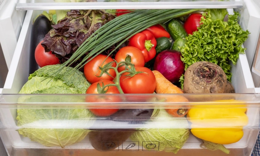 Cassetto delle verdure del frigo pieno di verdure e ortaggi