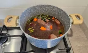 Vino rosso aggiunto alla pentola con il manzo e le verdure