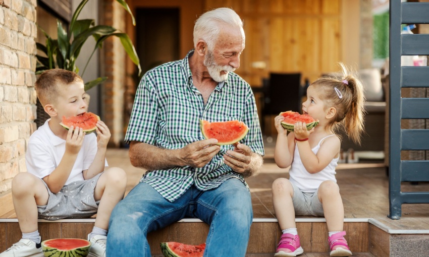 Un nonno che mangia l'anguria insieme ai suoi nipotini