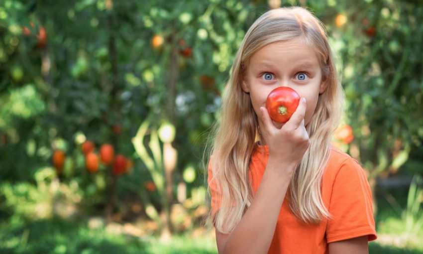 bambina con un pomodoro in mano