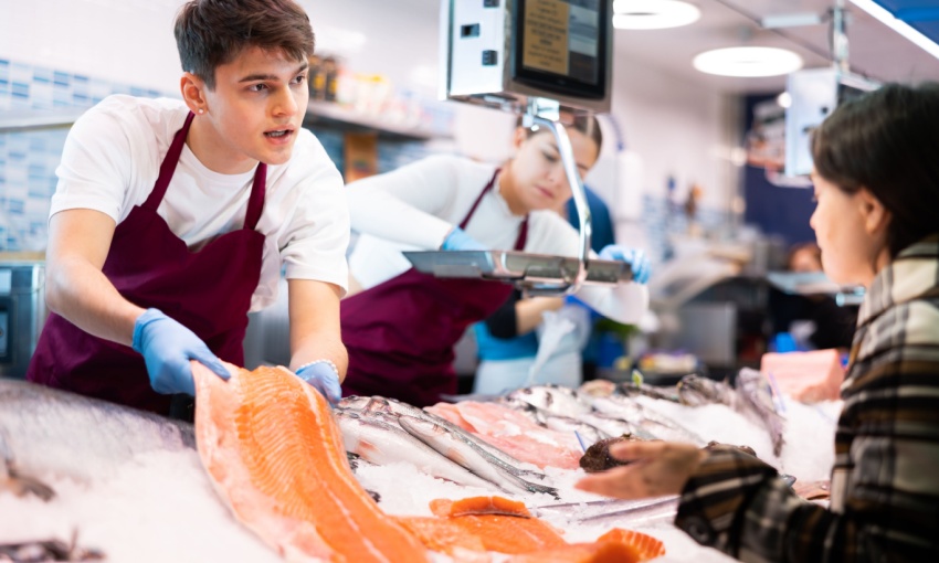 pescivendolo che vende salmone a una signora